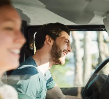Two people laugh while sitting in a car