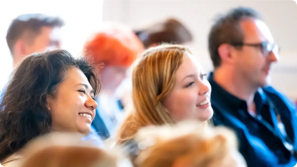 People smiling and listening attentively in a group setting.