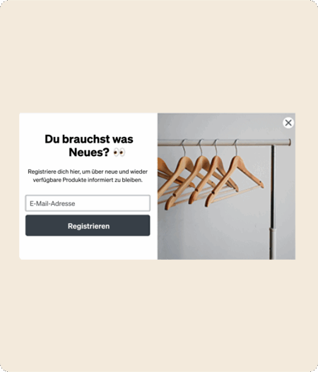 Anmeldeformular mit Text "Du brauchst was Neues?" und leeren Kleiderbügeln auf einer Stange.