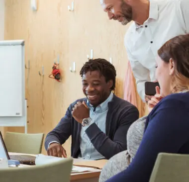 a group of colleagues smiling and laughing at a computer