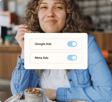 Woman in a restaurant eating, with overlay showing toggles for Google Ads and Meta Ads.