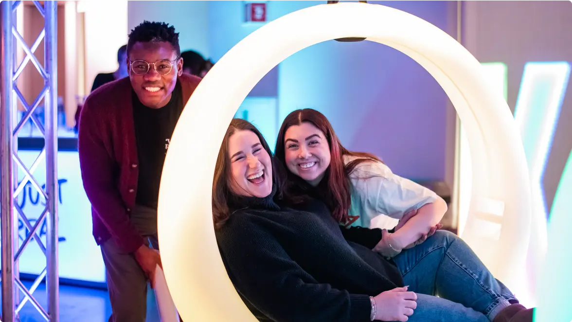 Klaviyo employees smile and laugh, one seated in a bright white, modern ring-shaped "seat" suspended from above