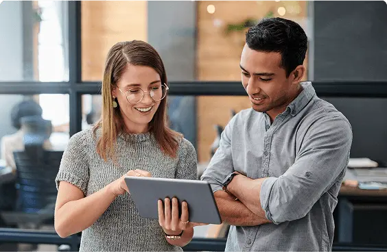 Photograph of 2 colleagues reviewing something on a tablet.