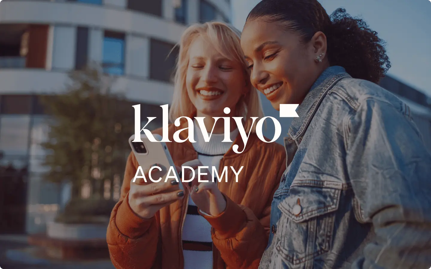 Two people smiling at a phone, with "Klaviyo Academy" text overlay.